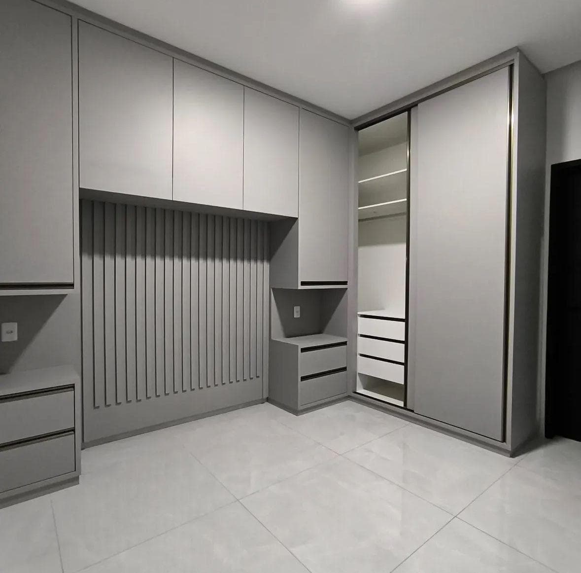 Armários cinza em quarto com painel ripado, gavetas e porta de correr