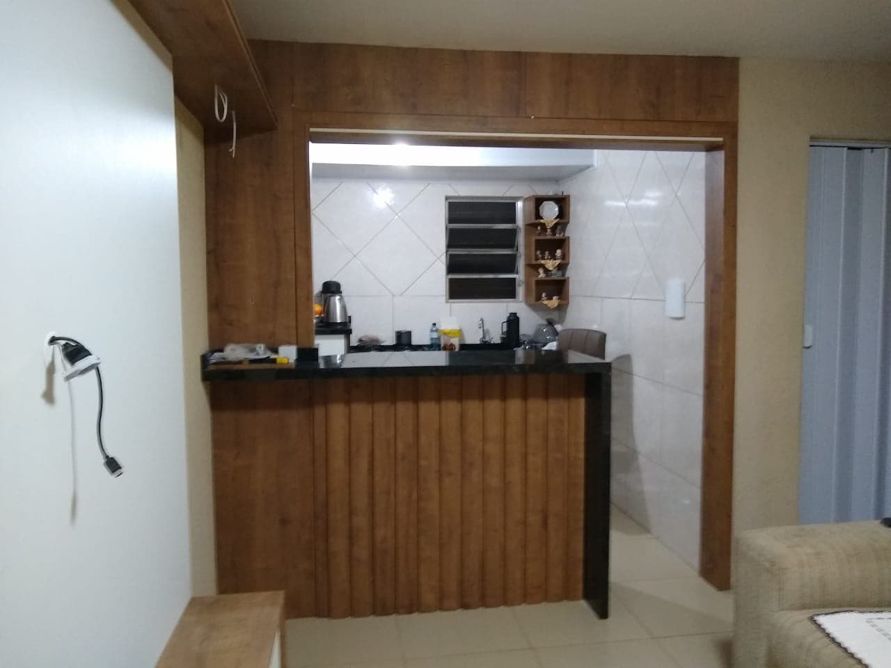 Balcão com frente ripada e acabamento de madeira em abertura para a cozinha