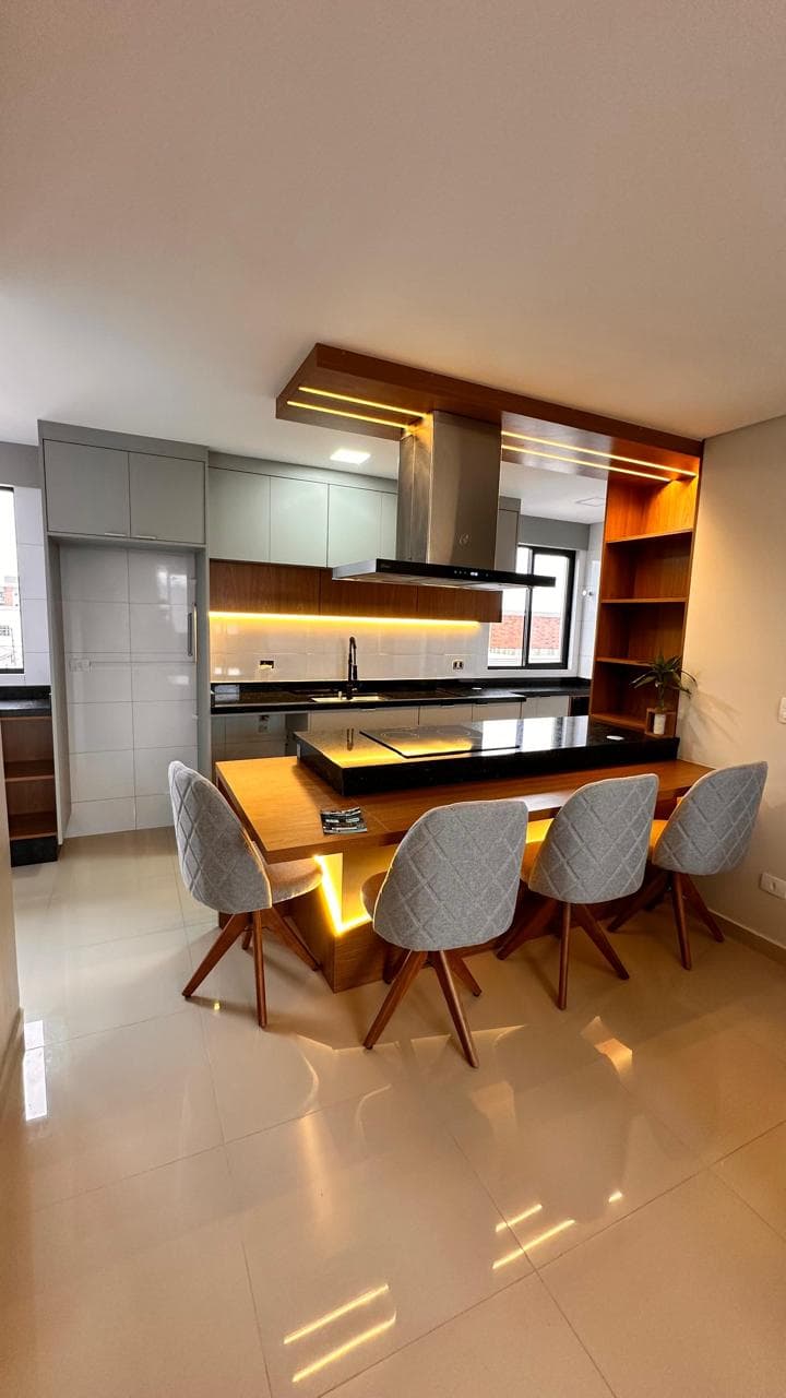 Cozinha com armários cinza, bancada de madeira e iluminação integrada